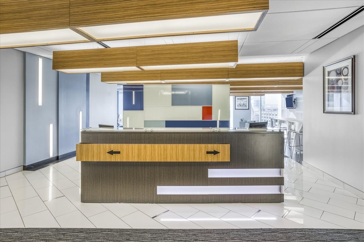 Modern reception desk at 222 Main Street with wood accents and stylish linear ceiling lights.