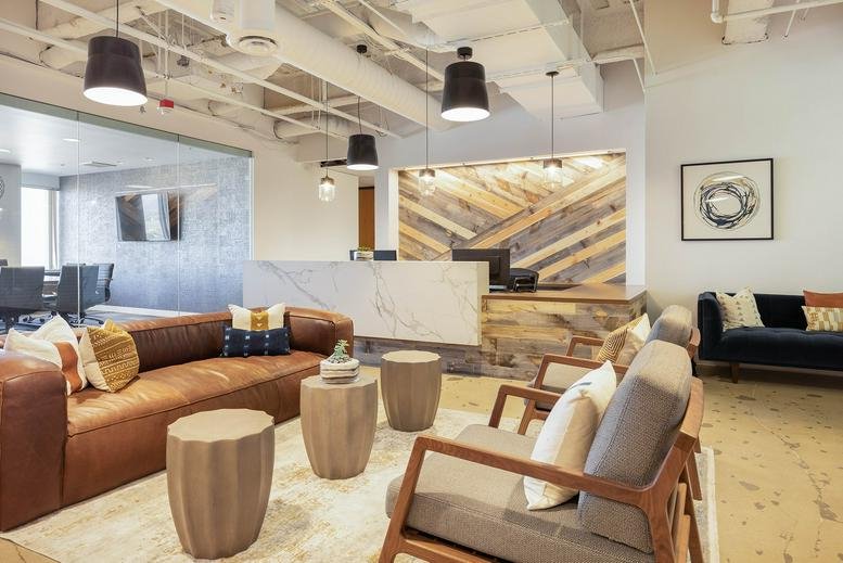 Bright reception area with a marble desk, wood-paneled feature wall, and leather sofa.