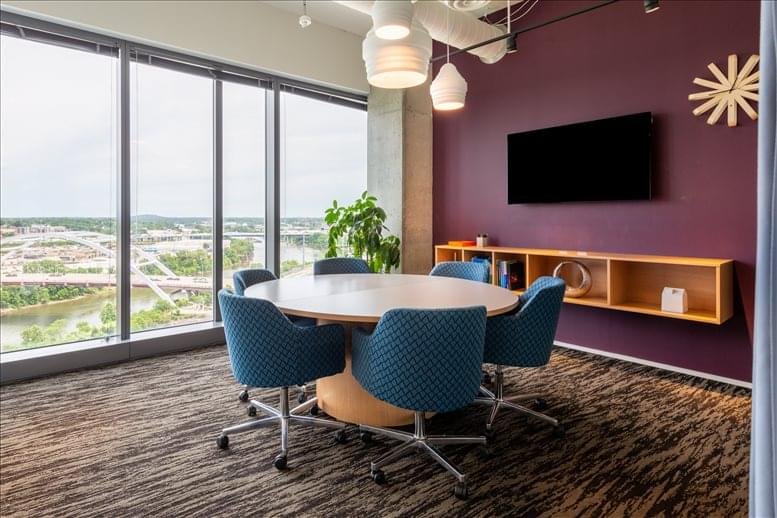 Well-lit boardroom with a circular table and blue ergonomic chairs overlooking the city.