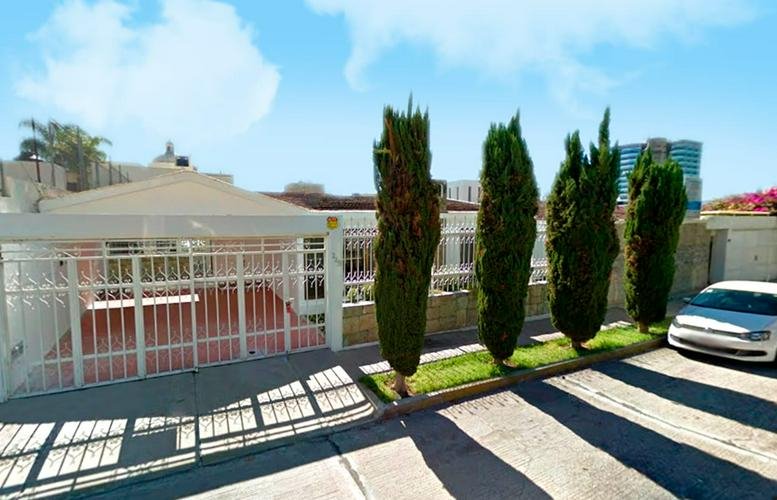 Exterior view of the Providencia Business Center, Aguascalientes with a gated entrance and manicured trees.