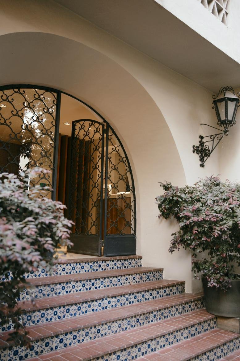 Arched entrance with ornate wrought iron gates and tiled steps at PÚBLICO, 225 Avenida Prado Norte.