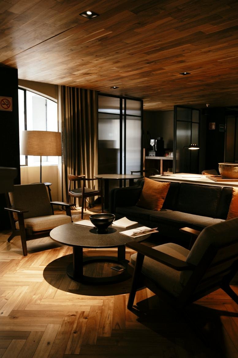 Sophisticated lounge area with a wooden ceiling, chevron floors, and comfortable mid-century armchairs.