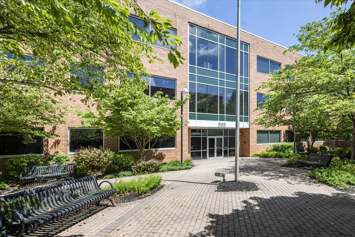 Exterior of the brick and glass facade at Gateway Corporate Center with shaded benches and trees.