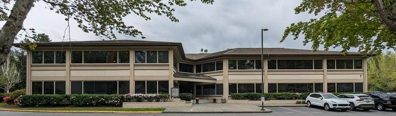 Exterior view of the low-rise Meadow Creek Business Center building surrounded by lush trees.