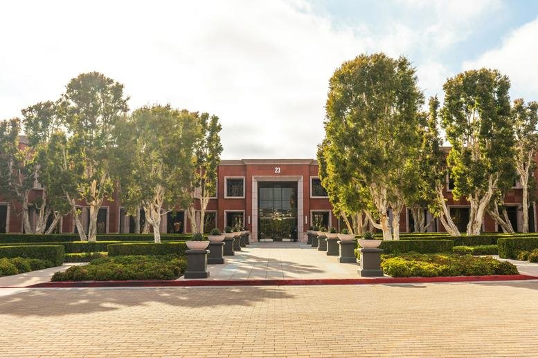 Exterior view of the brick facade and manicured gardens at 23 Corporate Plaza Dr.