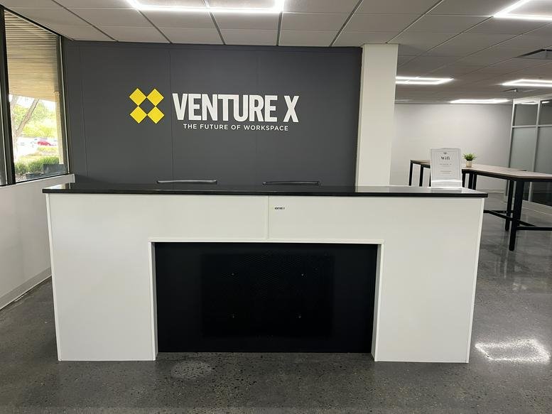 Branded reception area at Venture X Skillman, 23 Orchard Road, Montgomery with a sleek white and black desk.