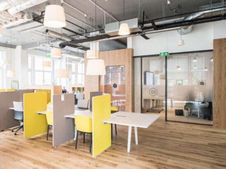 Spacious open-plan workspace at 230 Park Avenue, New York City featuring yellow desk dividers and wooden flooring.