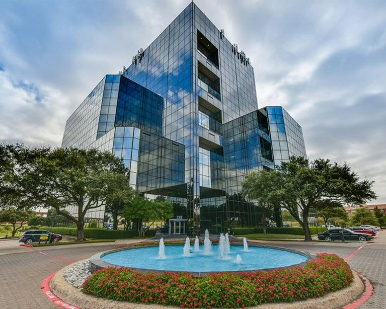 Exterior view of the glass-facade 2300 Valley View Ln building with a central fountain and landscaping.