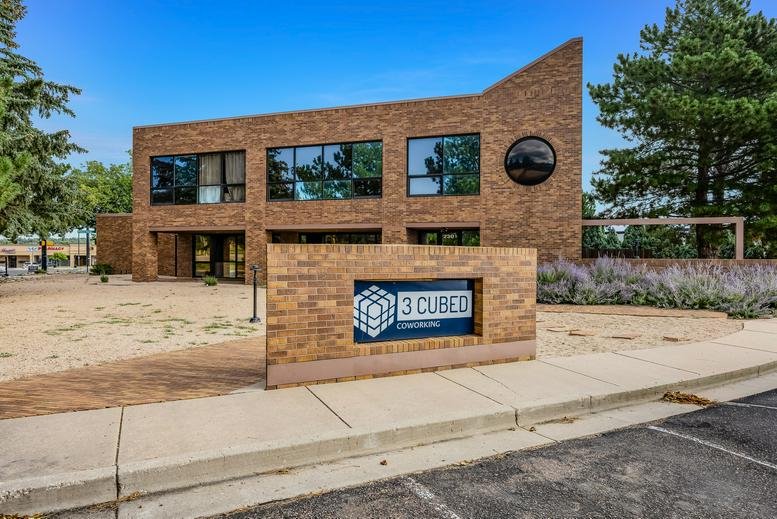 Exterior brick facade of 3 Cubed Coworking with modern windows and prominent signage.