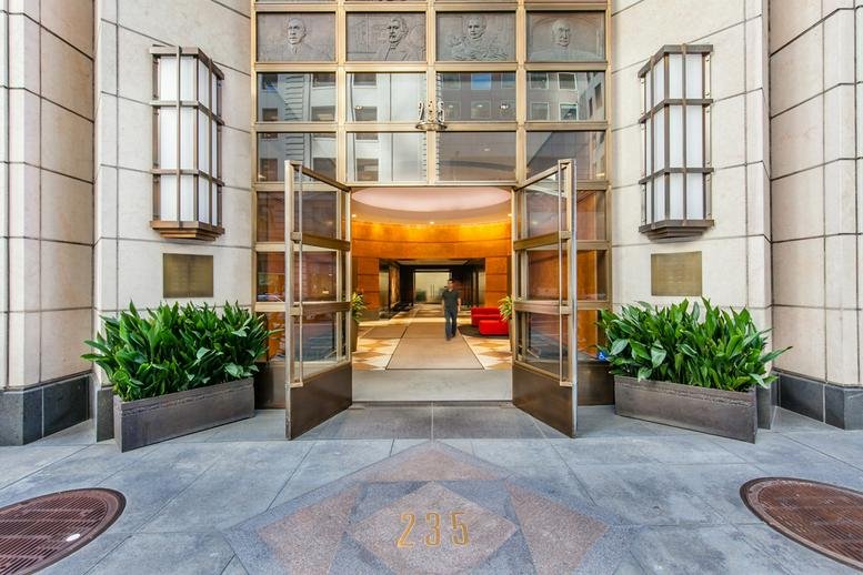 The grand gold-framed glass entrance to the 235 Pine Street, 7th Floor building.