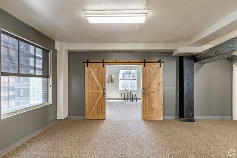 Empty room with barn doors and carpeted floors.