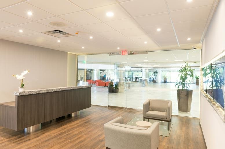Bright reception area at 2390 East Camelback Road with wood flooring and a modern dark wood desk.