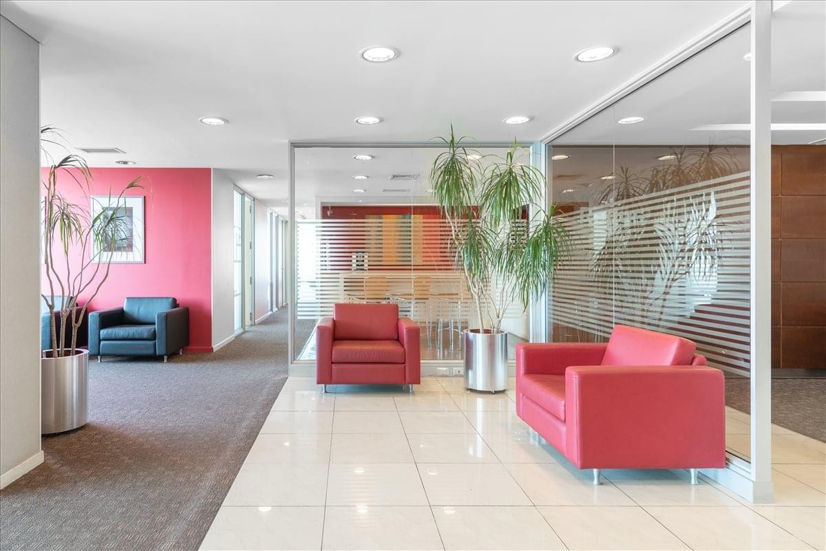 Vibrant reception lounge featuring pink accent walls, red seating, and indoor greenery.
