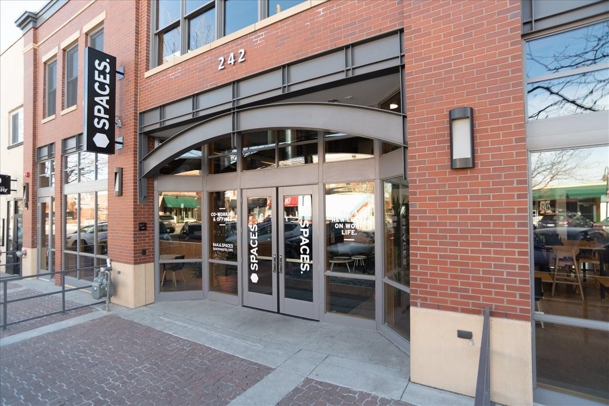 Exterior brick facade and glass entrance of the Spaces building at 242 Linden Street.