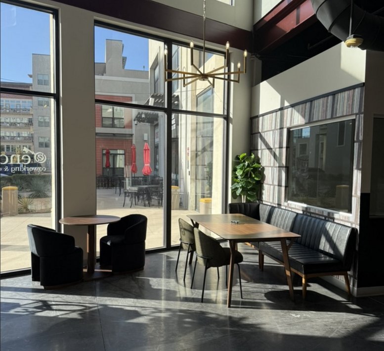 Bright communal lounge with large windows, modern seating areas, and a gold geometric chandelier.
