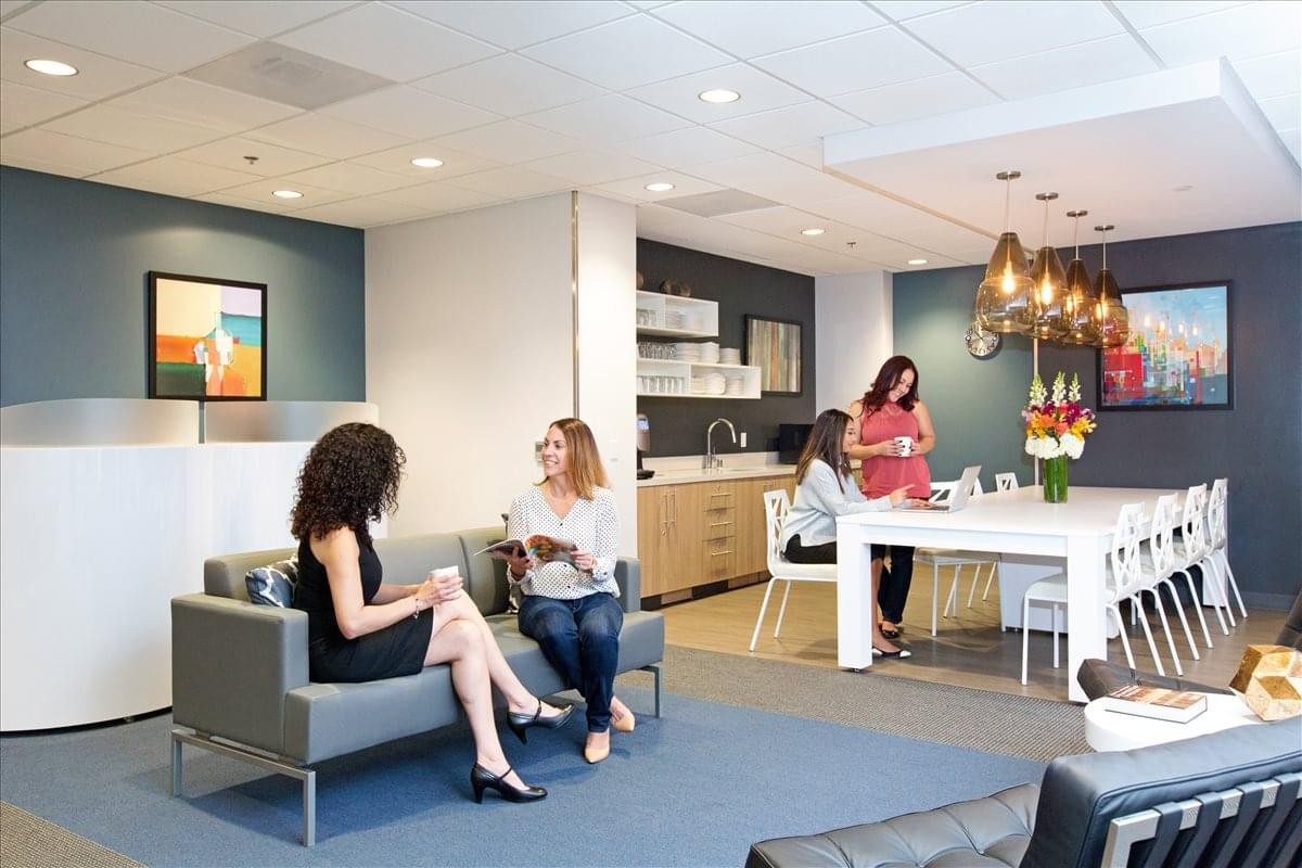Vibrant breakout space at 2447 Pacific Coast Highway with people relaxing on a grey sofa.
