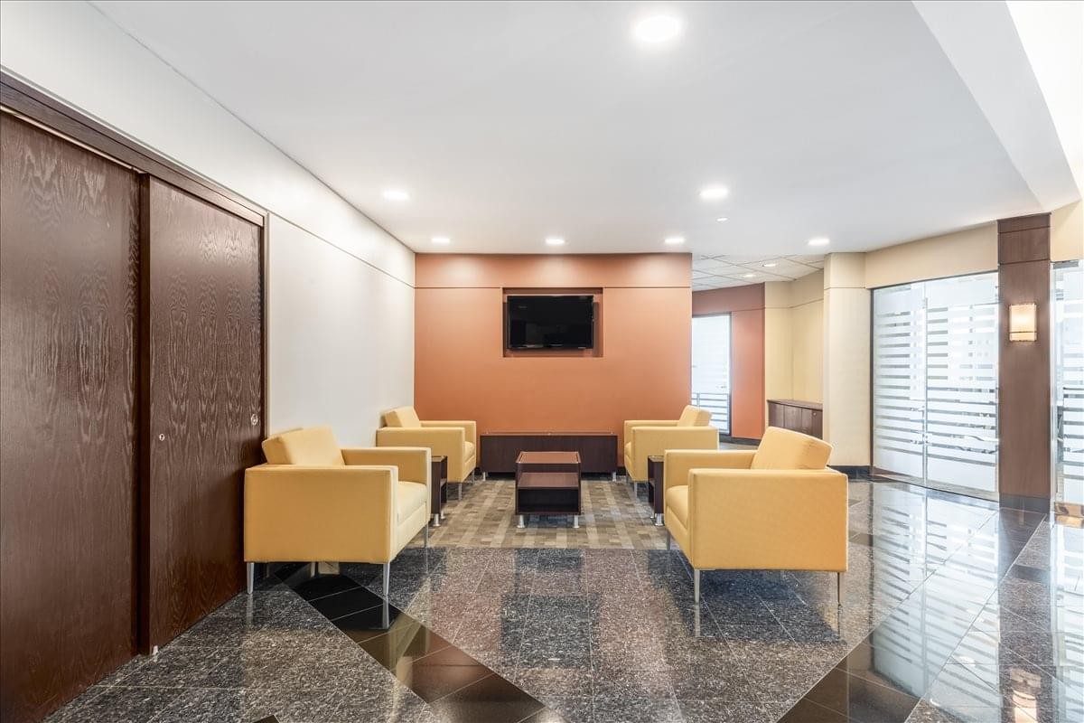 Reception lobby at First Street Center with yellow armchairs and a warm accent wall.