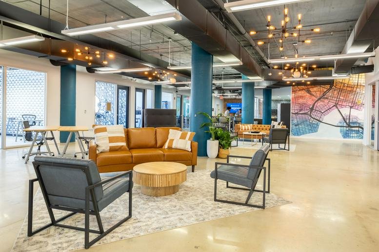 Spacious communal lounge with mid-century modern furniture and industrial ceilings.
