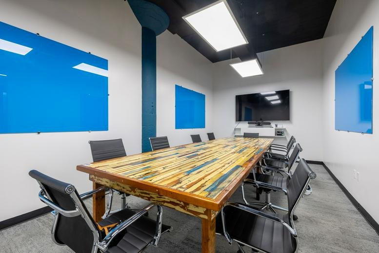 Conference room with a large live-edge wood table and blue whiteboards.