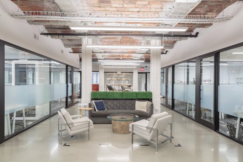 Spacious lounge at Industrious Bryant Park, 8th Floor, 25 W 39th Street, New York City with grey sofa and white armchairs.