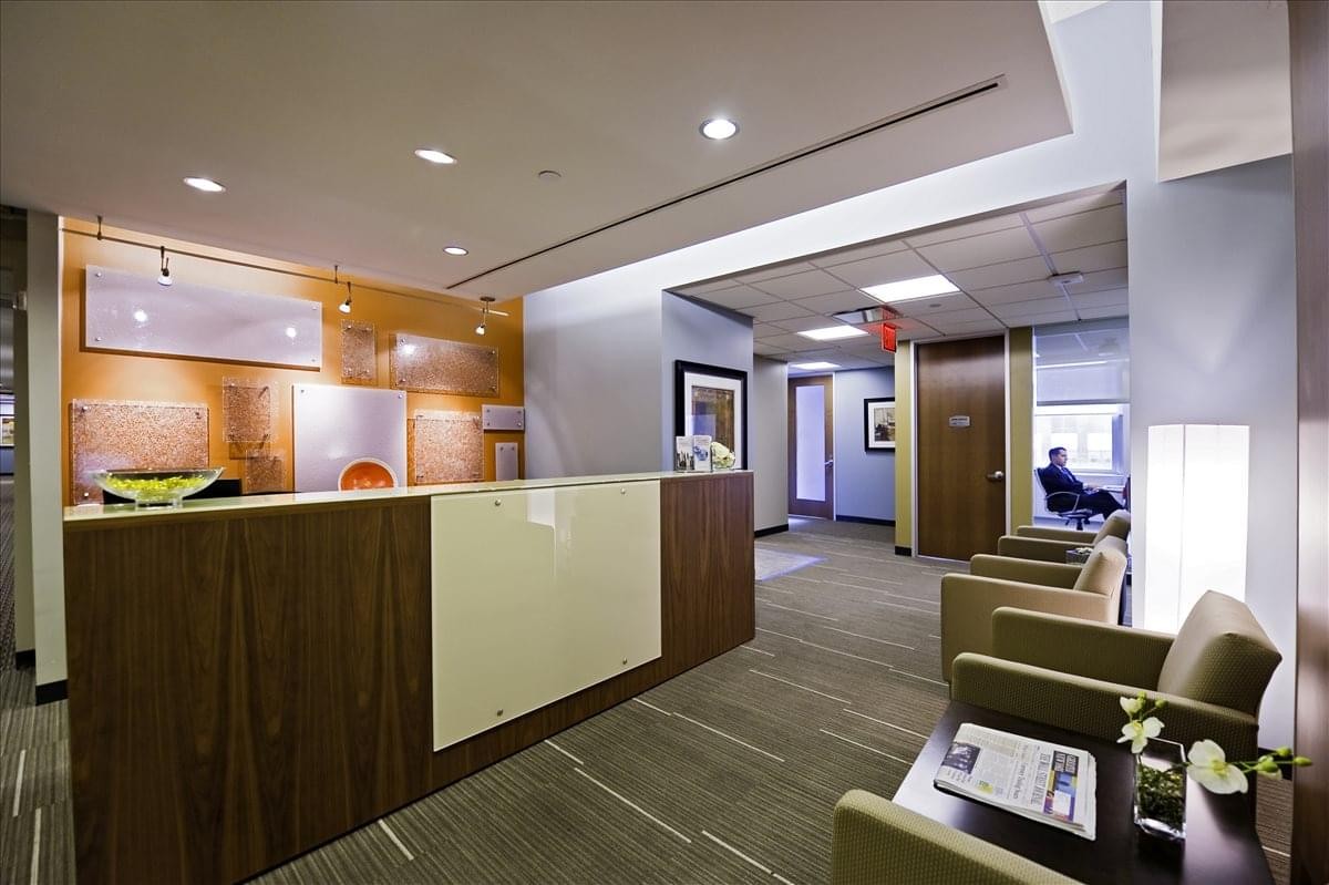 Modern reception area at 250 Park Avenue featuring a wood-panelled desk and bright lounge seating.