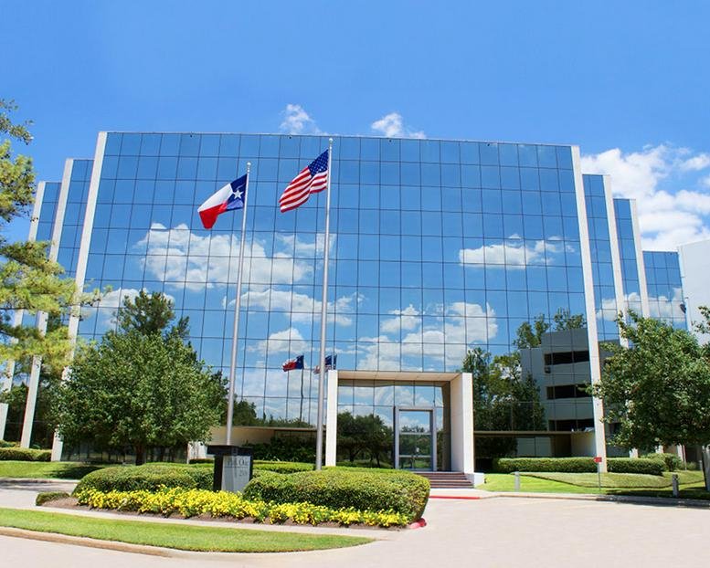 Exterior view of the blue glass-facade building at 2500 E TC Jester Boulevard under a bright sky.