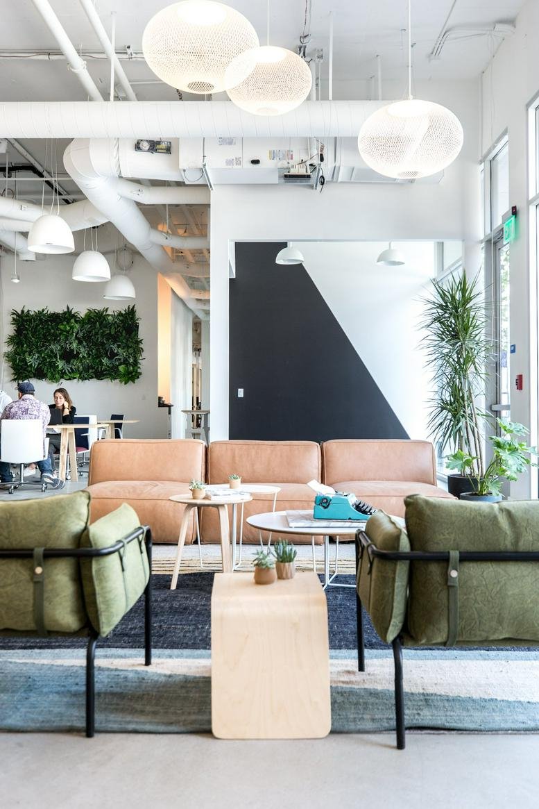 Bright, modern lounge with leather sofa, green armchairs, and orb light fixtures.
