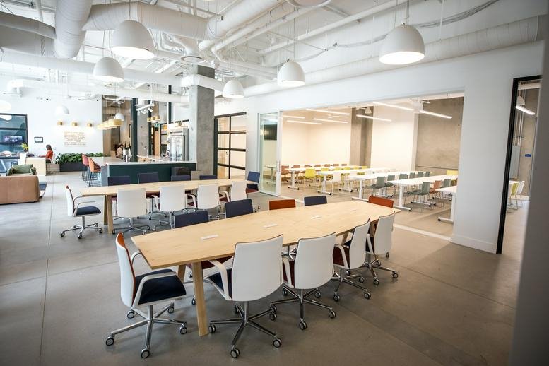 Spacious open-plan common area at Union Cowork, North City, San Marcos with large wooden tables and white chairs.