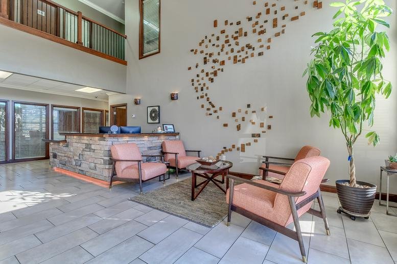 Spacious lobby at Mon Abri Business Center with stone reception desk, seating, and high ceilings.