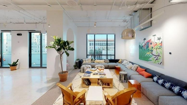 Spacious communal lounge at 255 Giralda Avenue with a large sectional sofa, wooden chairs, and vibrant wall art.