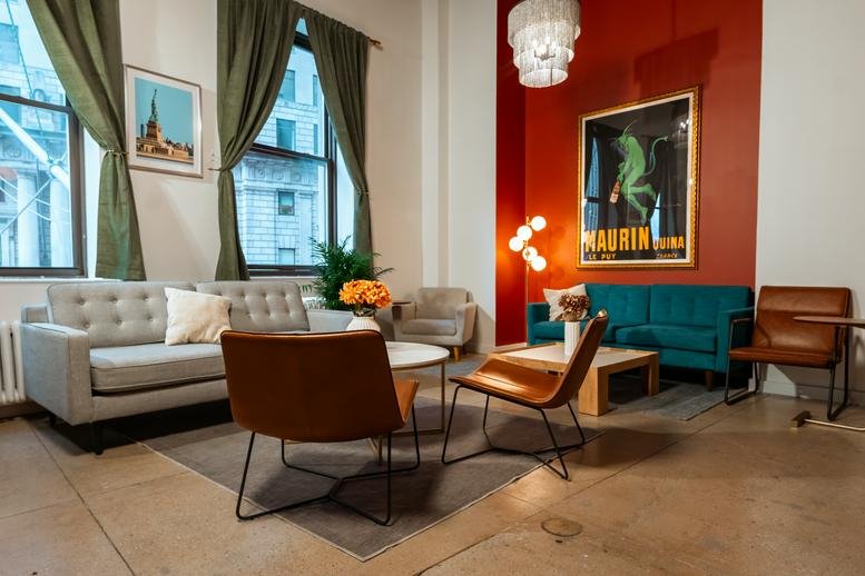 Spacious lounge at 26 Broadway with a red feature wall, colorful sofas, and vintage artwork.