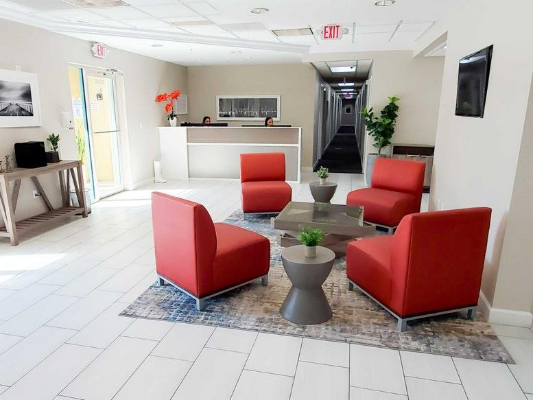 Lobby and reception area at Lakeside Workspaces with modern red armchairs and a sleek front desk.