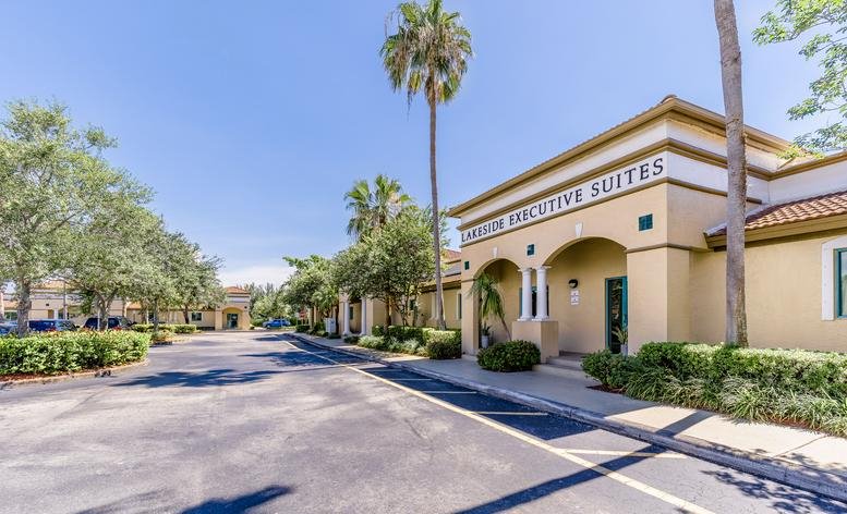 Exterior view of the Lakeside Workspaces building with palm trees and a sunny parking lot.