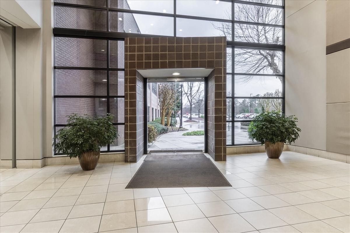 Bright glass-enclosed building entrance for 2700 Corporate Drive with indoor plants and natural light.