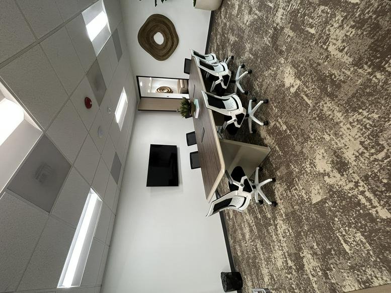 Boardroom featuring a large table, wall-mounted screen, and decorative wall art.