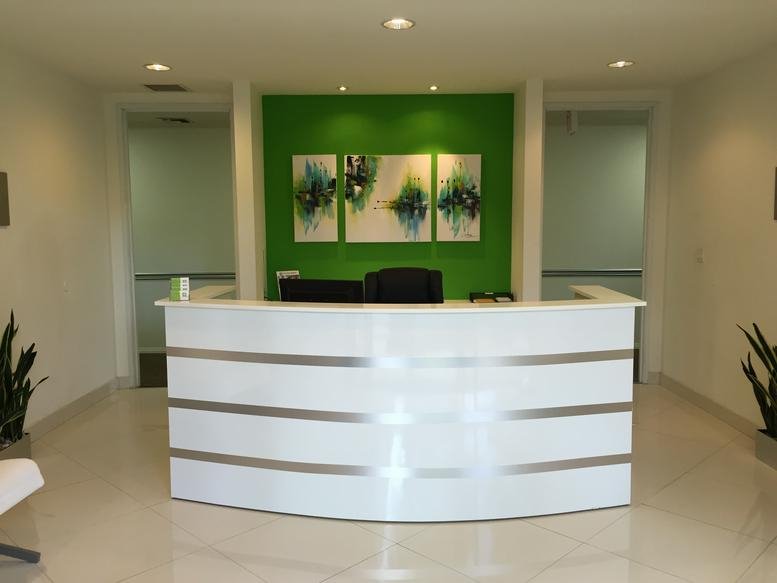 Reception at 27281 Las Ramblas, Suite 200, with a bright green feature wall and curved white desk.