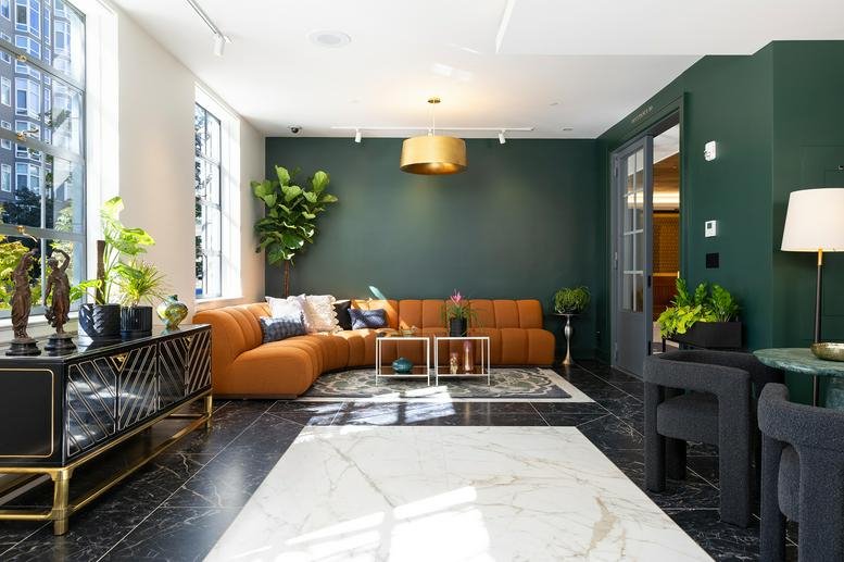 Spacious lounge area with dark green walls and leather sofa.