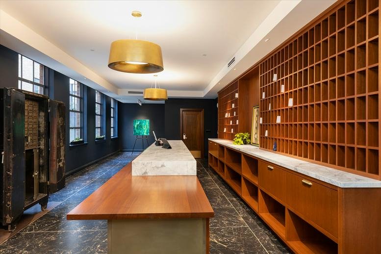 Elegant reception area of Labour Temple with a long wood and marble desk and gold pendant lights.
