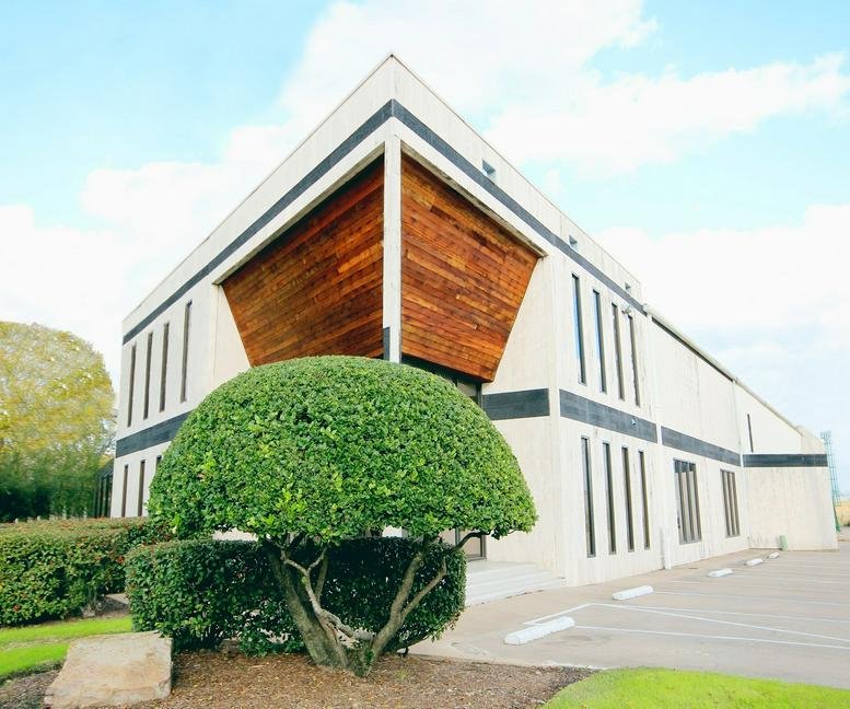 Exterior facade of the modern office building at 2800 Antoine Drive with wood paneling and manicured greenery.