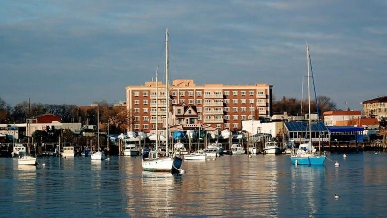 Waterfront view of the brick facade at Office on the Bay with several sailboats in the foreground.