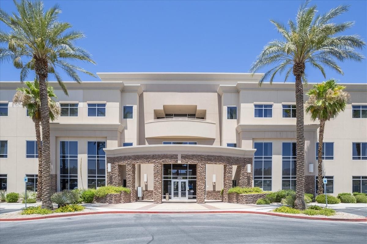 Exterior view of the Mediterranean-style Siena Office Park Center II with palm trees and a stone entrance.