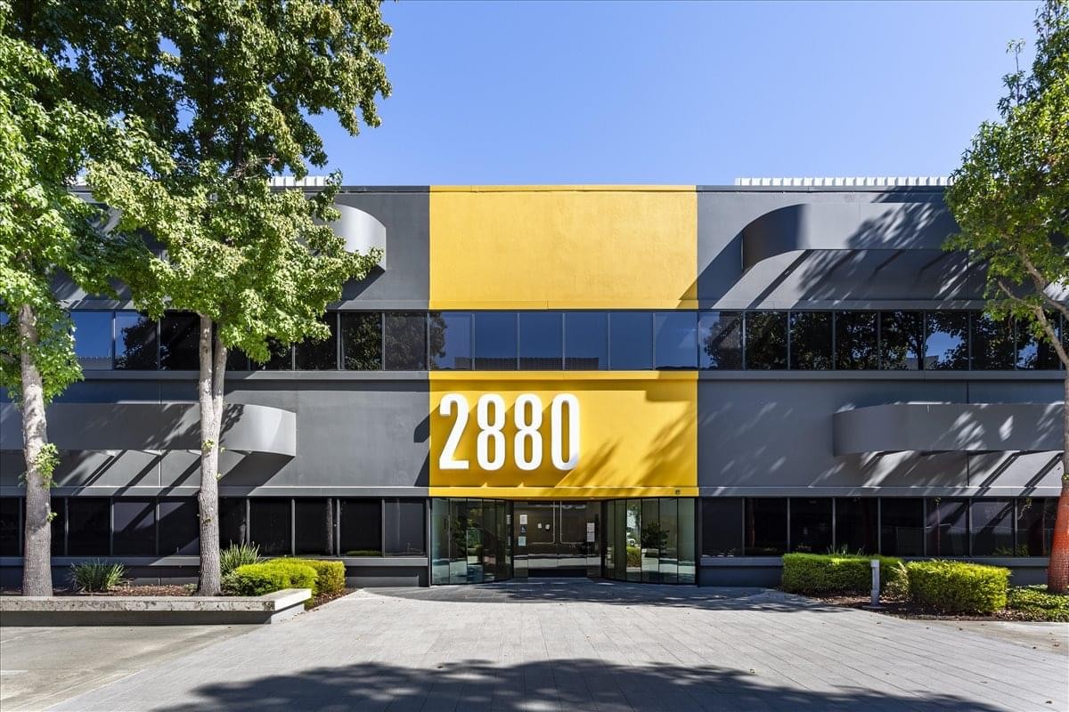 Exterior view of the dark grey and yellow facade of 2880 Zanker Road, Suite 230, North San Jose Center.