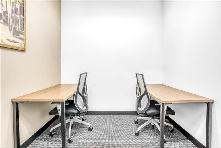 Internal two-person office suite with wooden desks and mesh chairs.