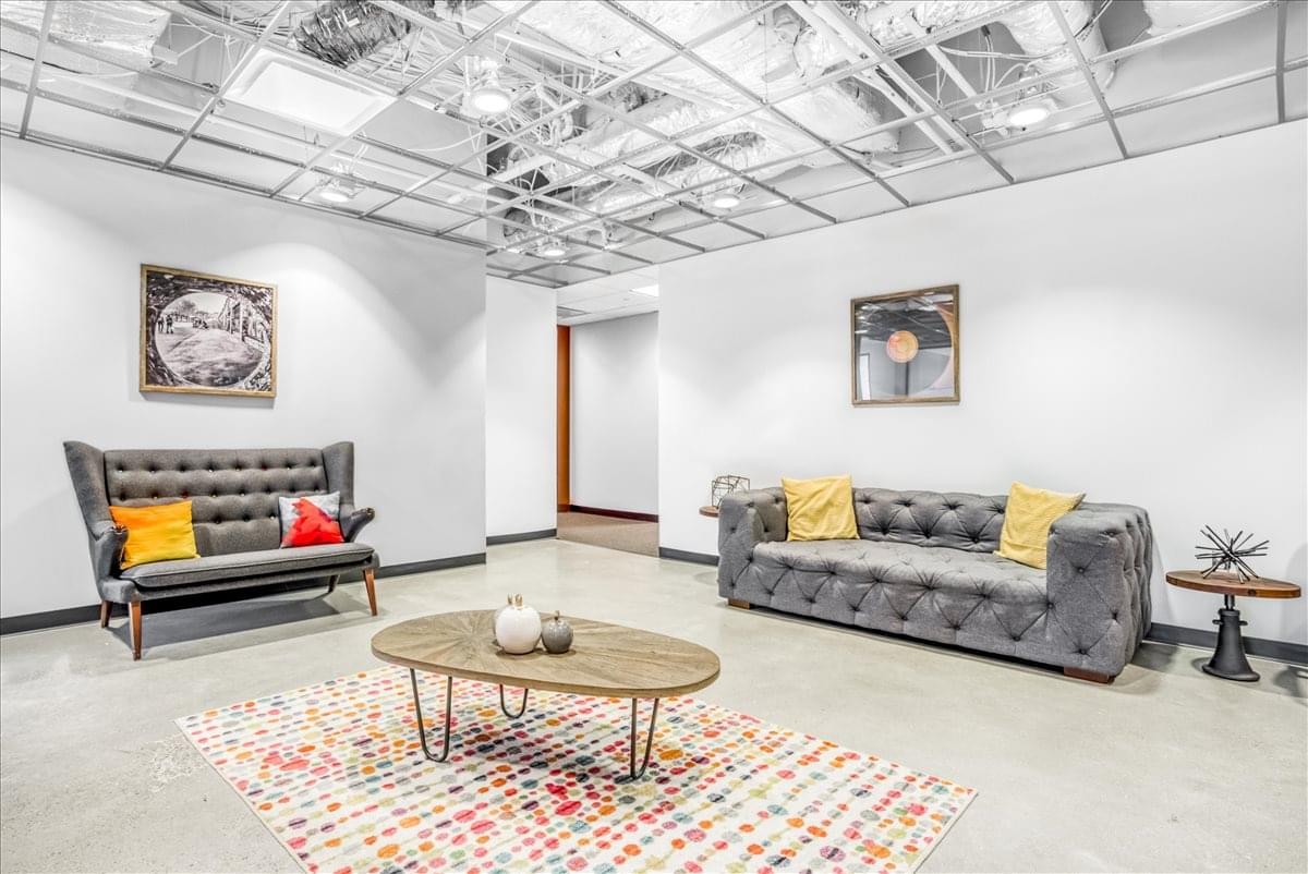 Spacious breakout lounge at CIRA Centre with tufted grey sofas and a colorful patterned rug.