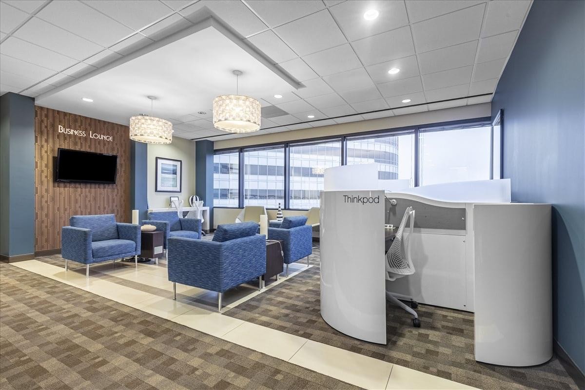 Bright lounge area with blue armchairs, wood paneling, and large windows.