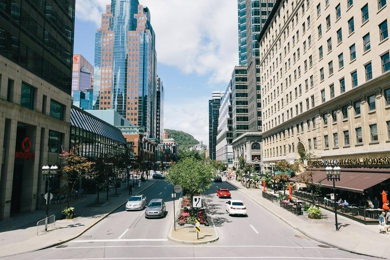 Street view of a wide city boulevard lined with large commercial buildings and cars.