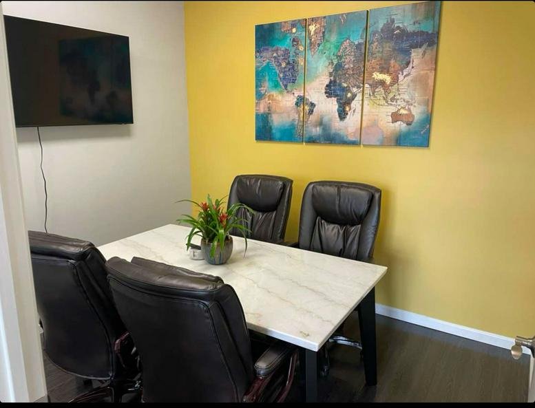 A professional meeting room at 30-97 Steinway Street, Suite 301A featuring a marble table and world map art.