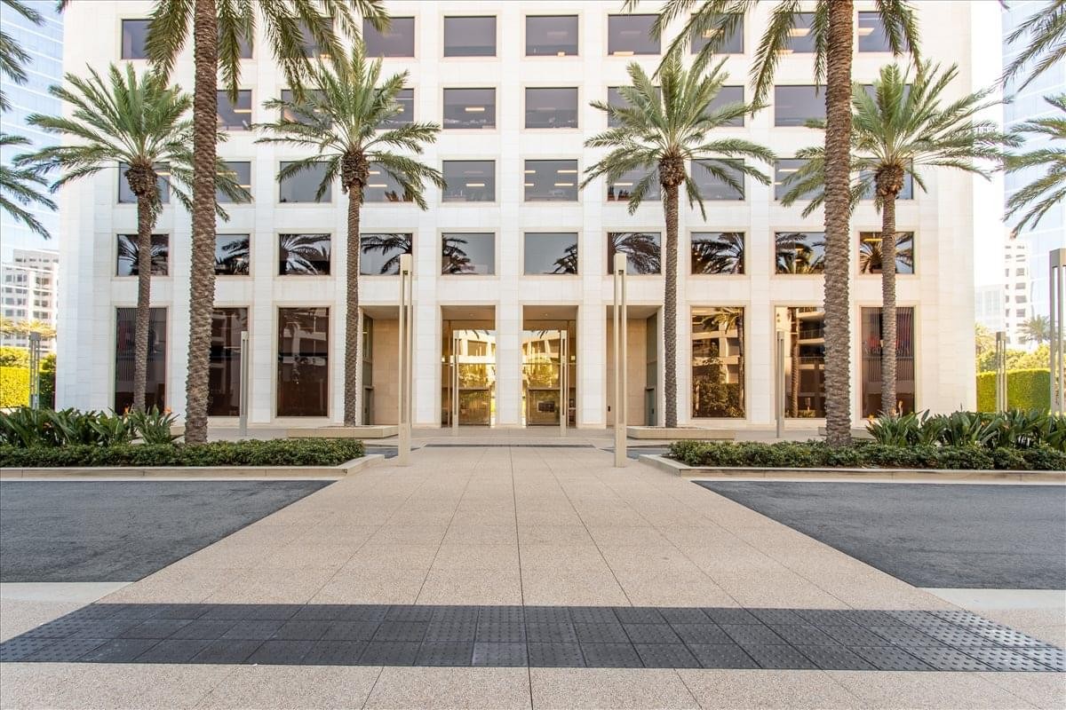 The modern white facade and palm-lined entrance of 300 Spectrum Center Drive.