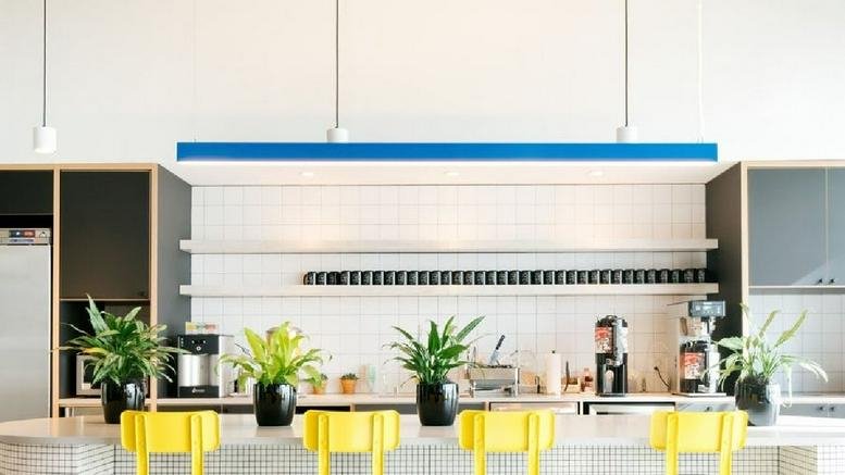 Modern communal kitchen at 3001 Bishop Drive with yellow chairs and indoor plants.