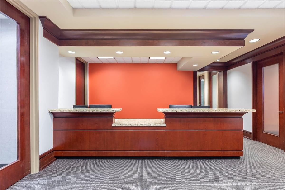 Modern reception desk at 303 Perimeter Center North, Suite 300 with an orange accent wall.
